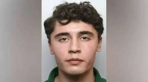 MET Police Shot of Daniel Khalife, who has dark curly hair and wears a green shirt.