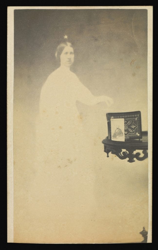 A double exposure photo showing a frame on a shelf, superimposed on the white figure of a woman